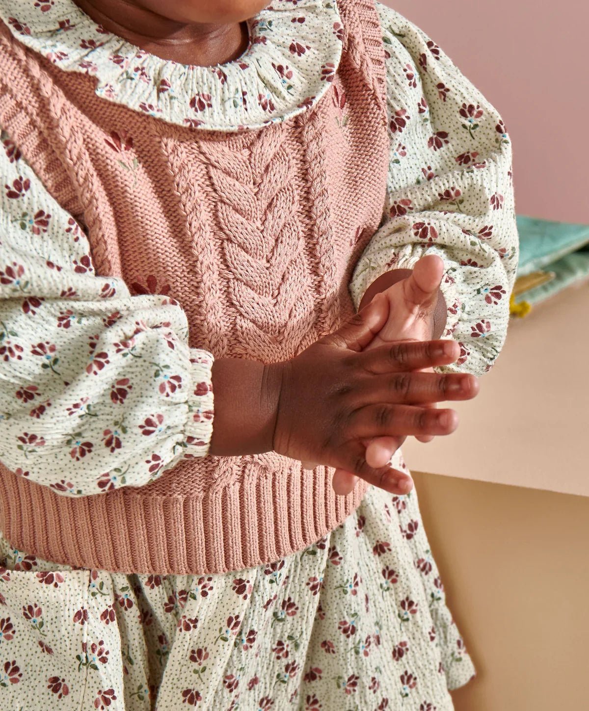 Pink cable-knit vest and floral dress with frilled collar, close-up