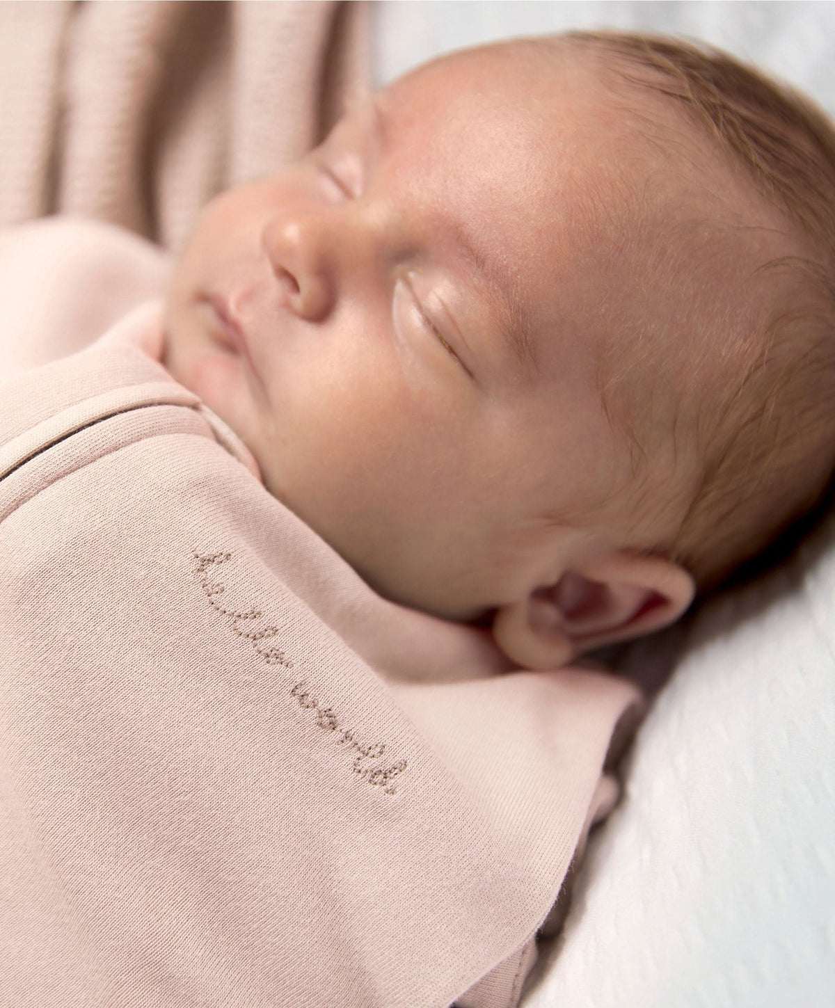 Pink zip-front swaddle sleeping bag close-up, newborn asleep