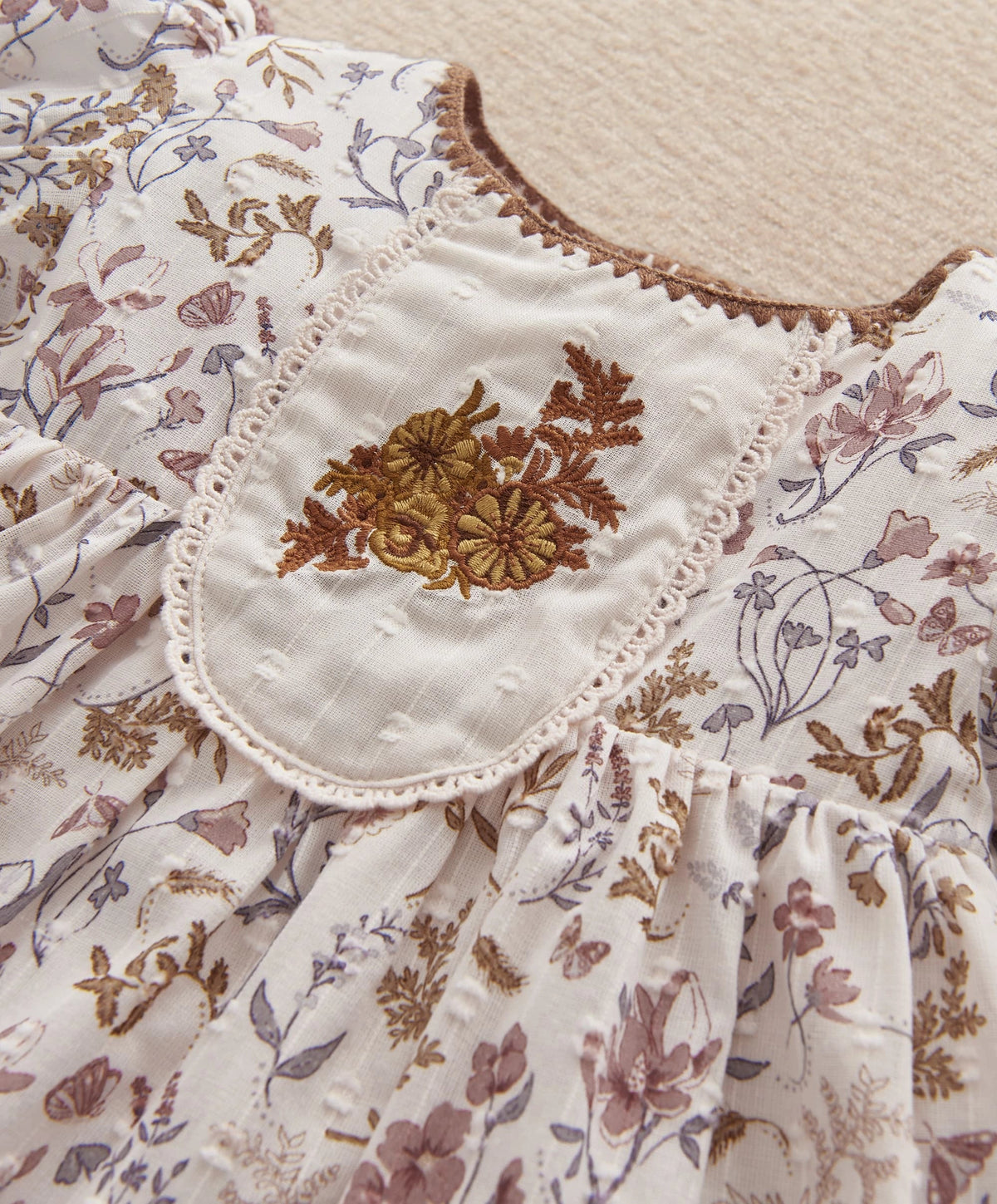 Floral dress bodice close-up with embroidered bib, lace trim and puff sleeves