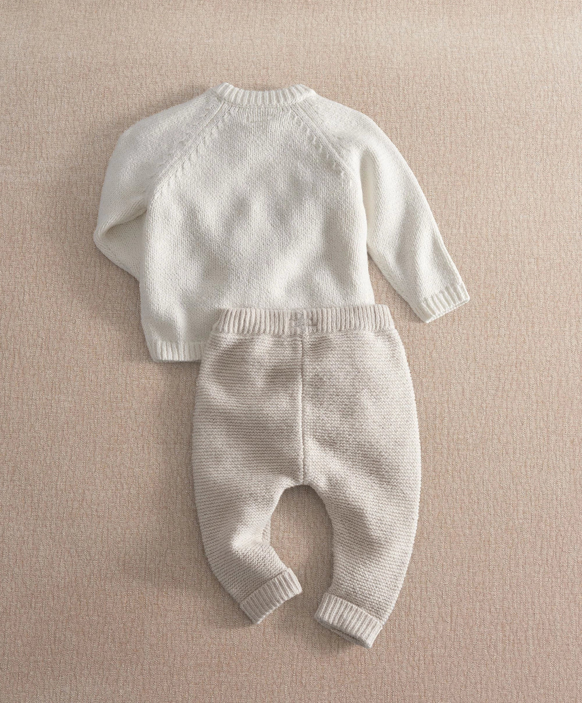 Cream knit 2-piece baby set, long-sleeve top and pants with ribbed cuffs and hem (back).