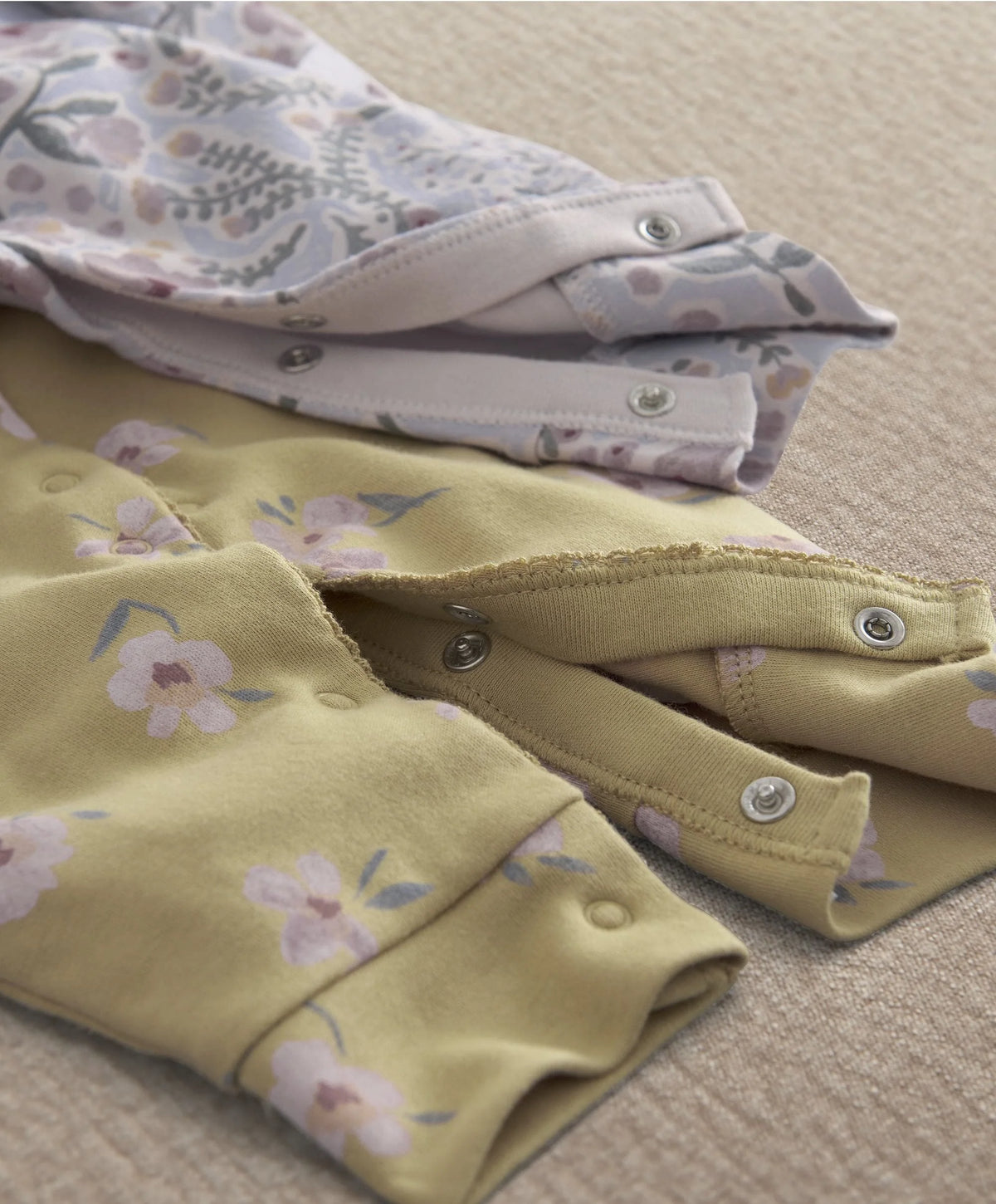 Folded baby rompers with floral fabric and snap buttons at leg opening