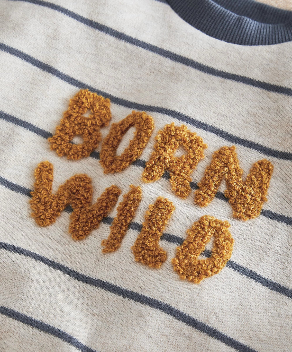 Close-up of striped T-shirt with fuzzy 'Born Wild' embroidered-style letters