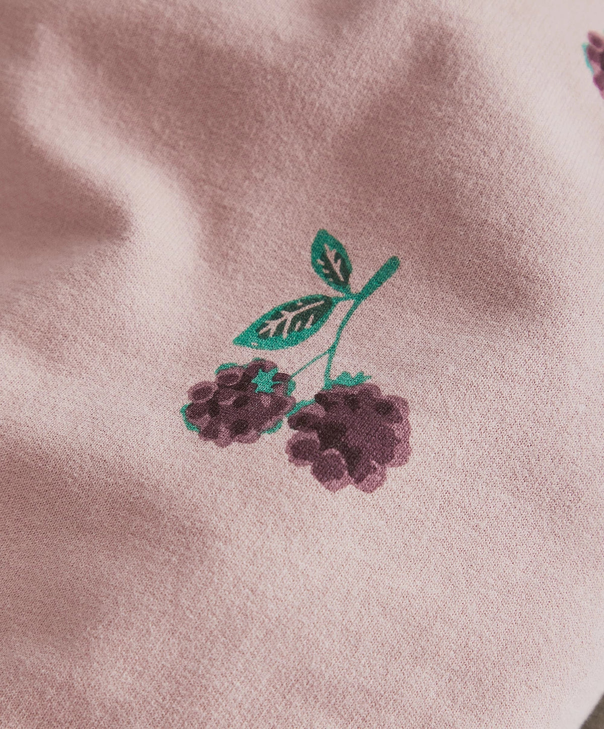 Pink fabric with green leaves and dark berry bramble print