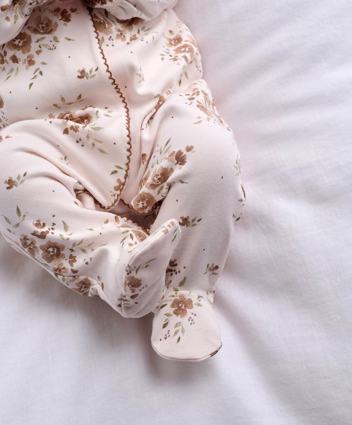 Off-white floral all-in-one detail with footed cuffs and gathered front placket.