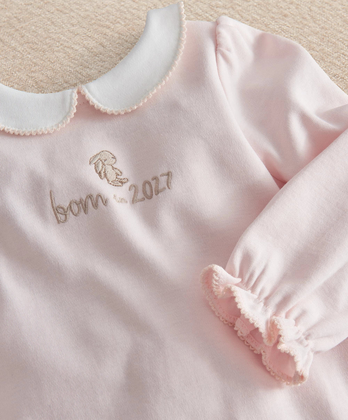 Pink baby onesie with embroidered bear, 'born in 2027' and ruffled sleeve cuffs