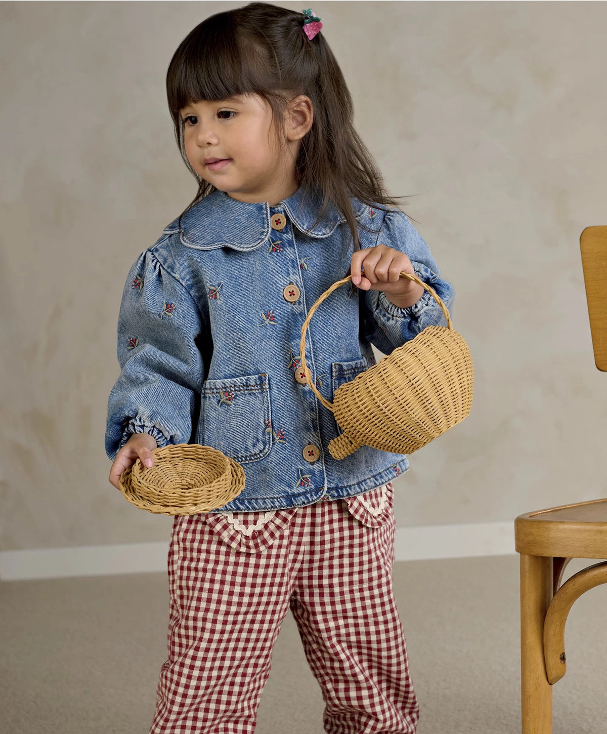 Light blue denim jacket with button front and embroidered motifs, child holding woven baskets