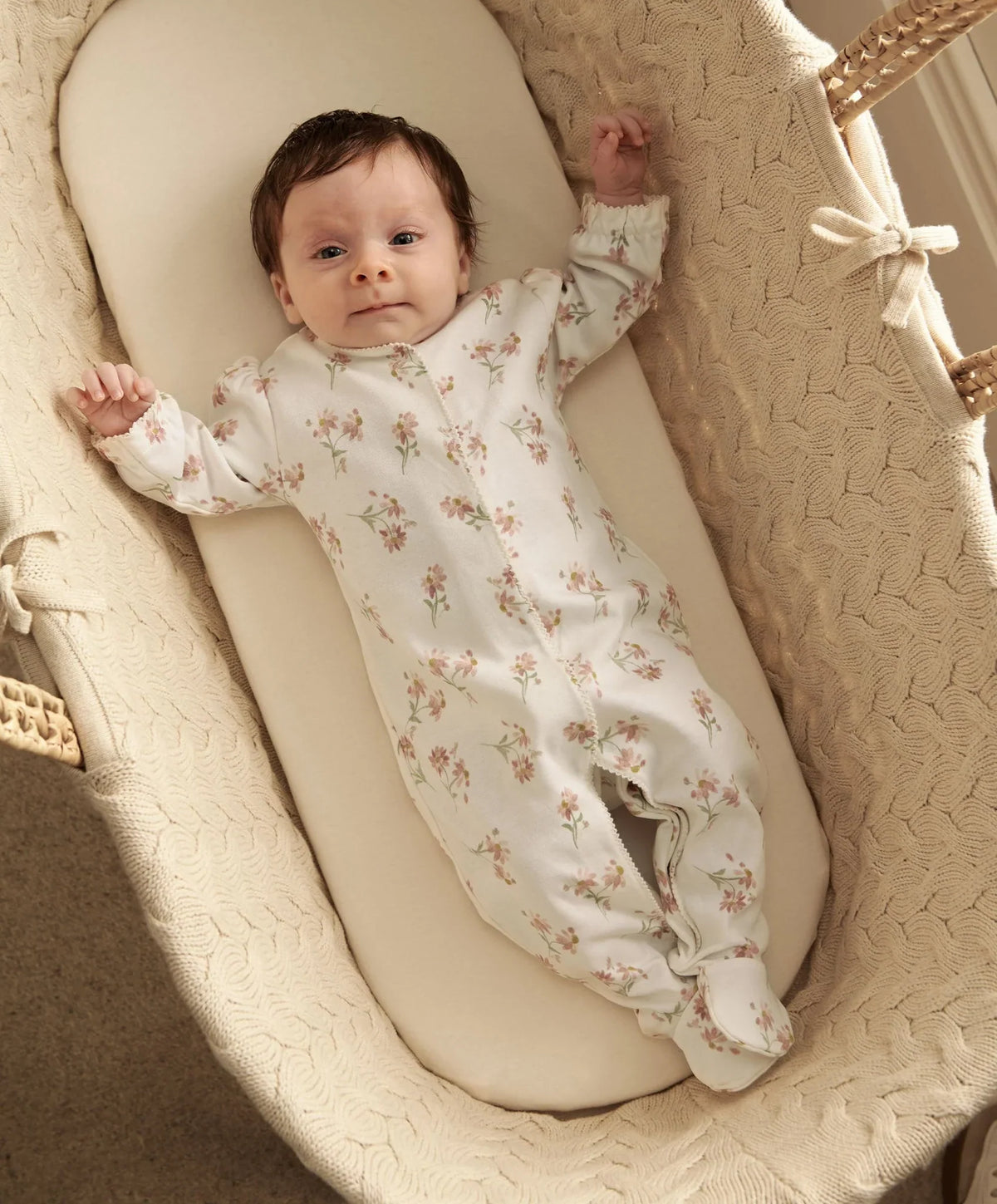 Daisy-print footed sleepsuit with long sleeves, white fabric and pastel floral pattern