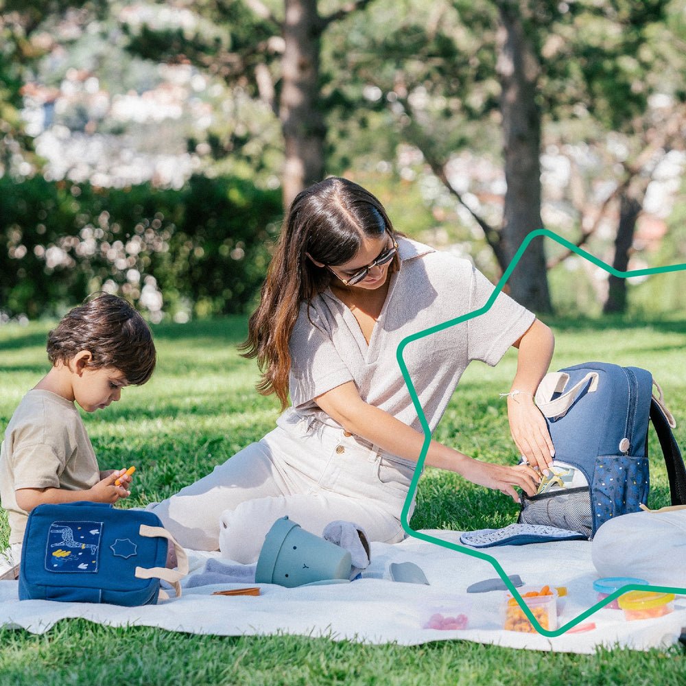 Navy changing backpack open on outdoor play mat, organizer compartments visible