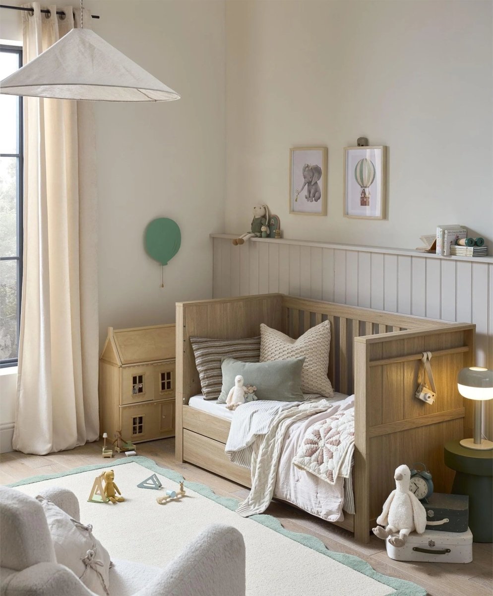 Oak cotbed with guard rails and slatted sides in nursery room