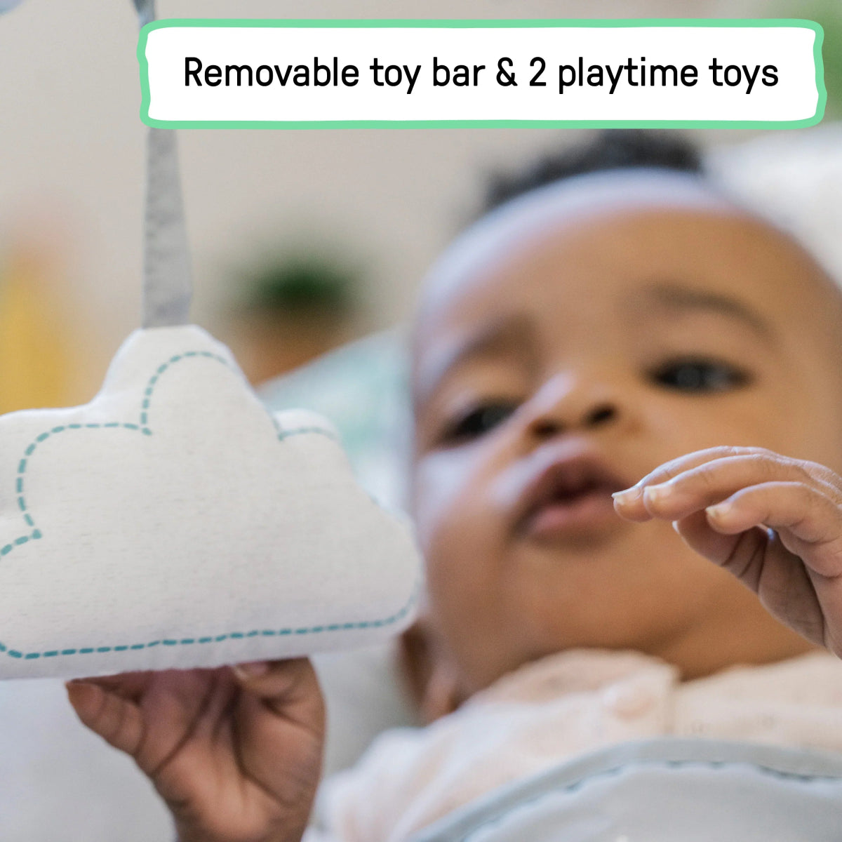 Baby reaching for plush toy on bouncer toy bar