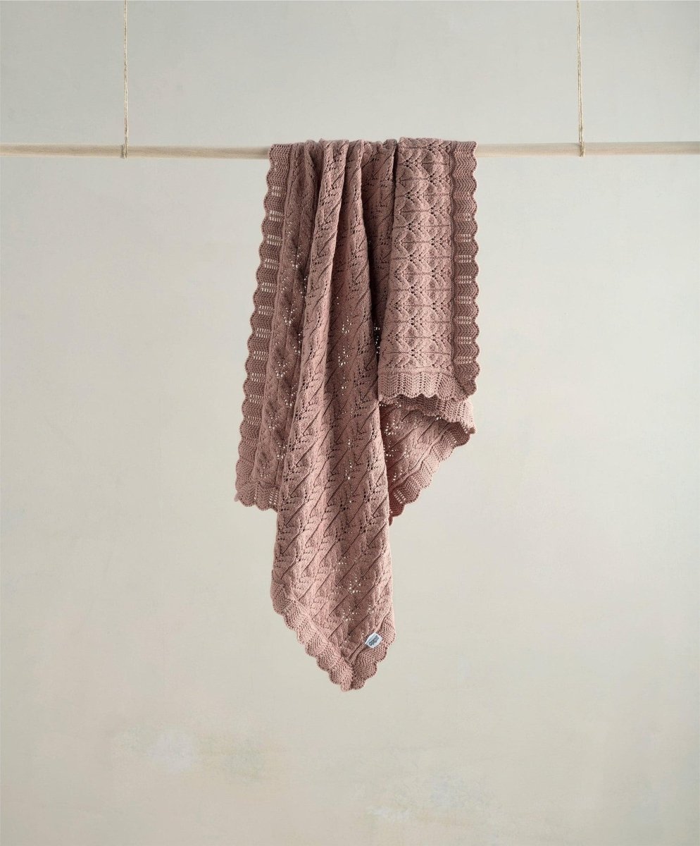 Knitted baby blanket in mauve with textured knit and scalloped trim