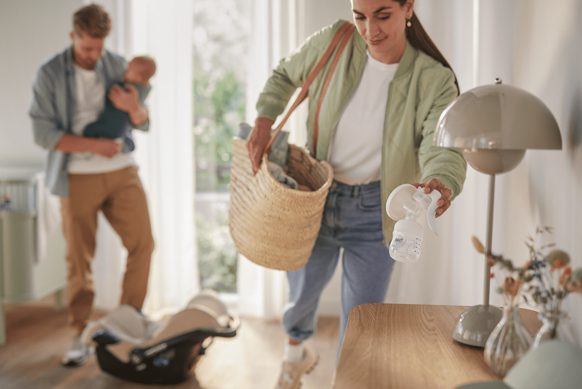 Manual breast pump with white bottle and shield, held by caregiver