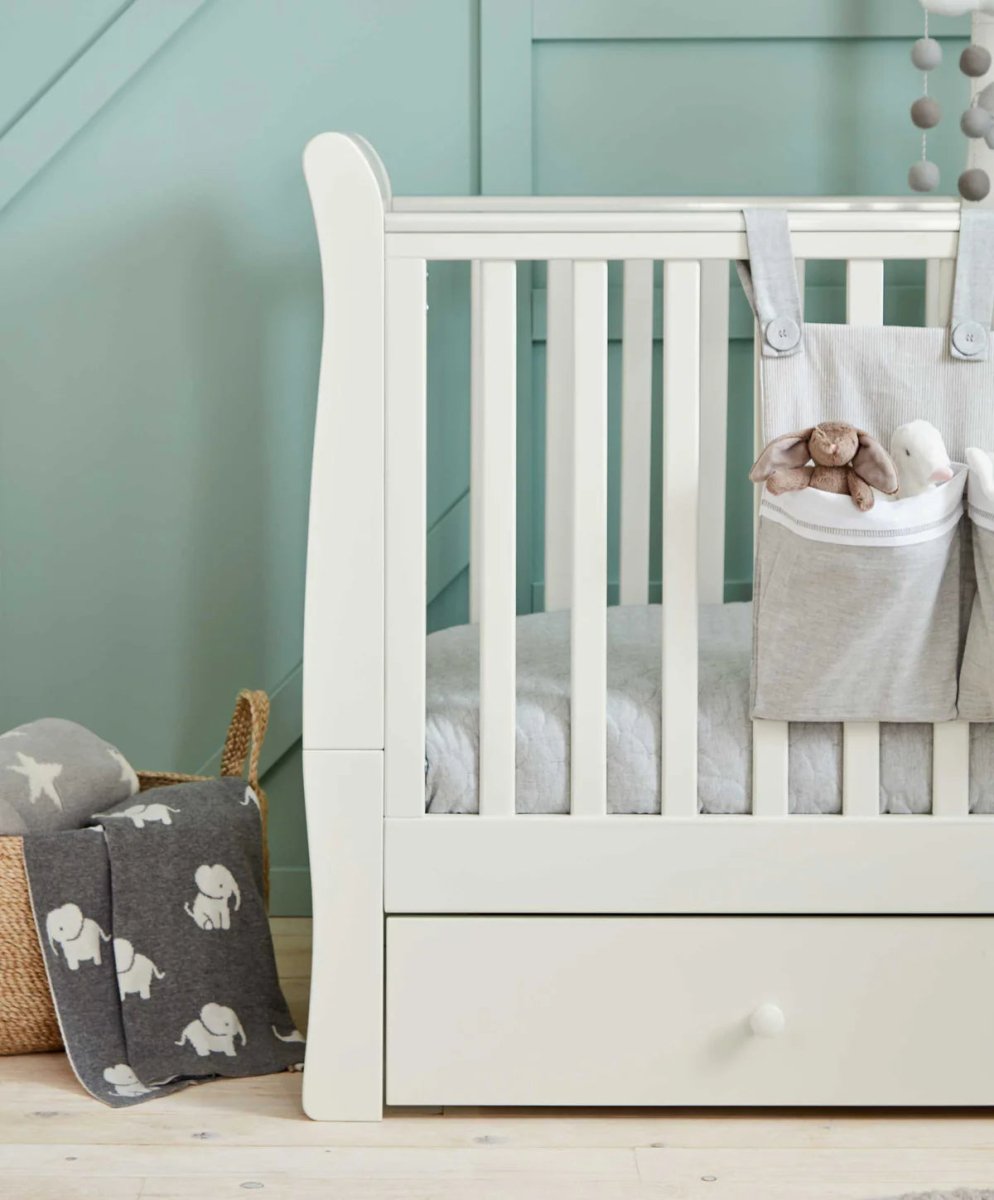 White Mia cotbed side with hanging storage and grey elephant cushion