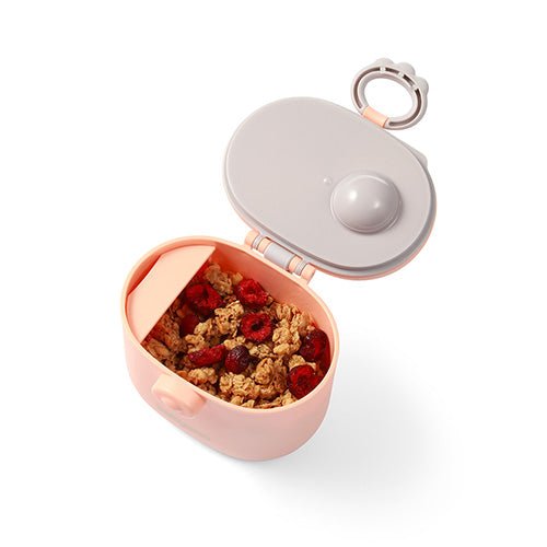 Milk powder dispenser with open lid, pink container holding cereal-like mixture