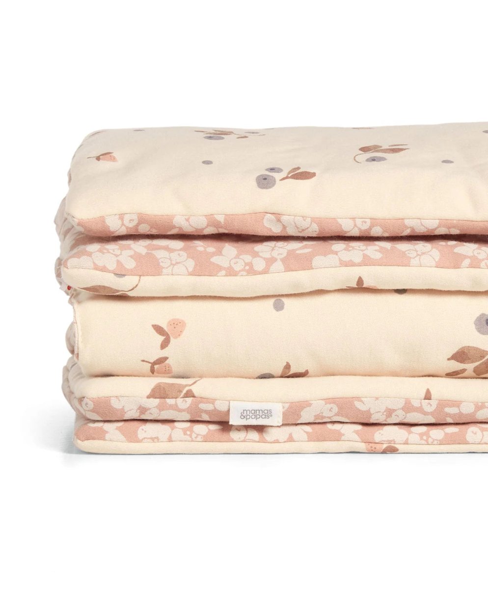 Folded quilt stack with cream and pink floral print, fabric label visible