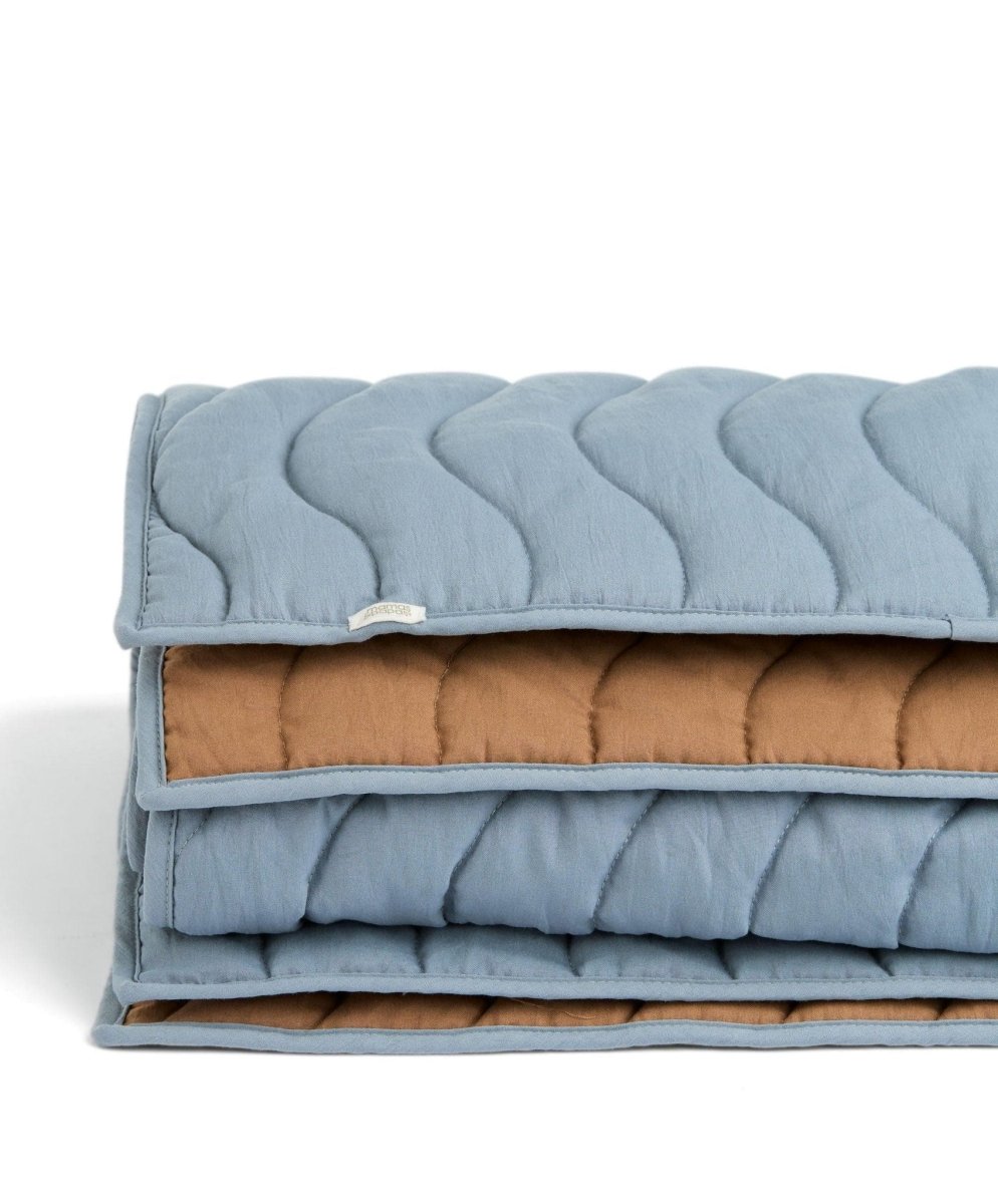 Stacked wave quilt layers: light blue top with brown lining and stitched wavy channels