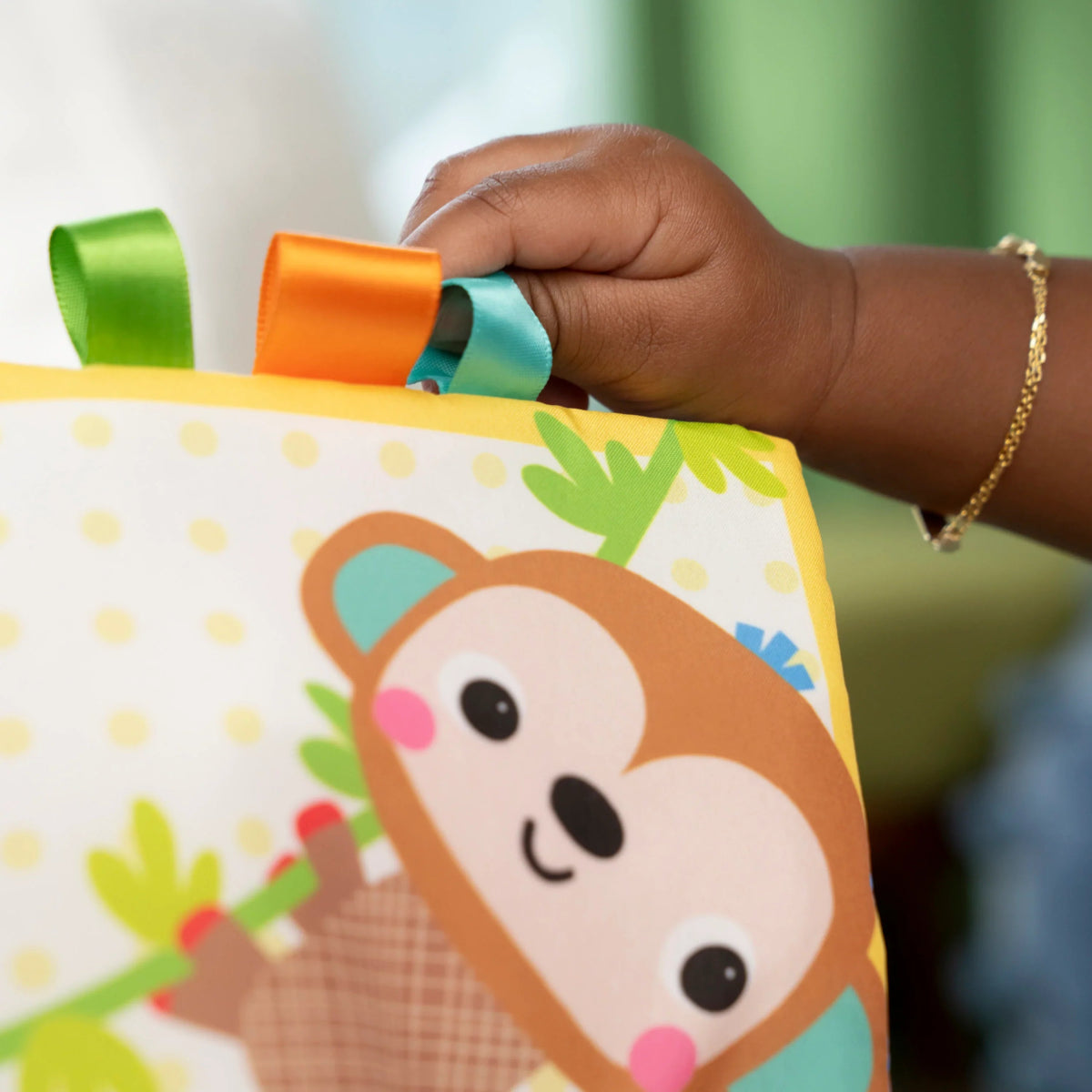 Soft cloth baby book close-up with bear cub face on fabric page and teal handle