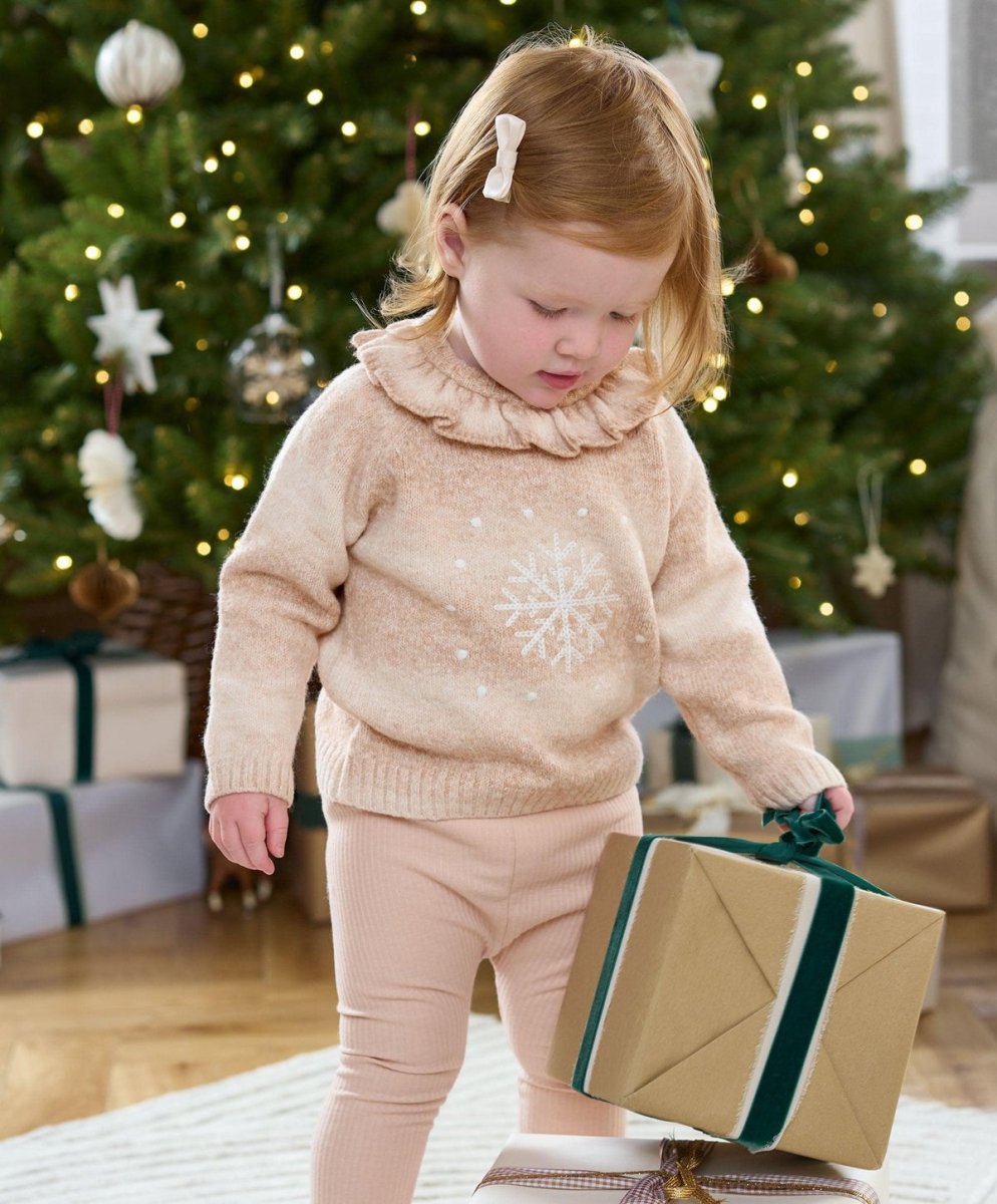 Light beige snowflake knit jumper with ruffled high neck on standing child