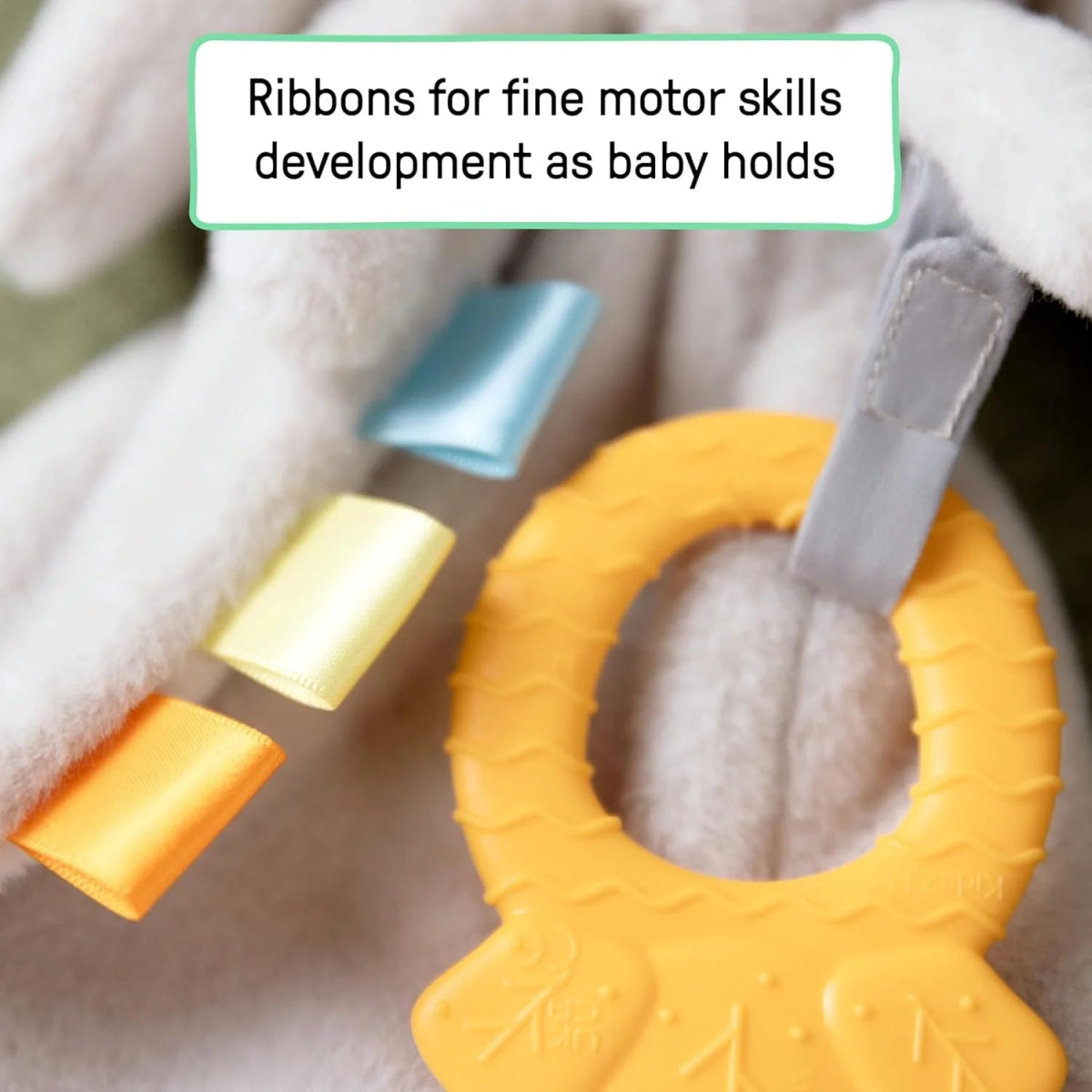 Close-up of plush bunny teether: yellow-orange ring with soft ribbon loops