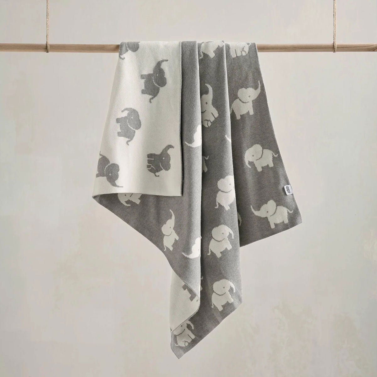 Grey knitted elephant blanket with allover elephant motif, soft fold drape