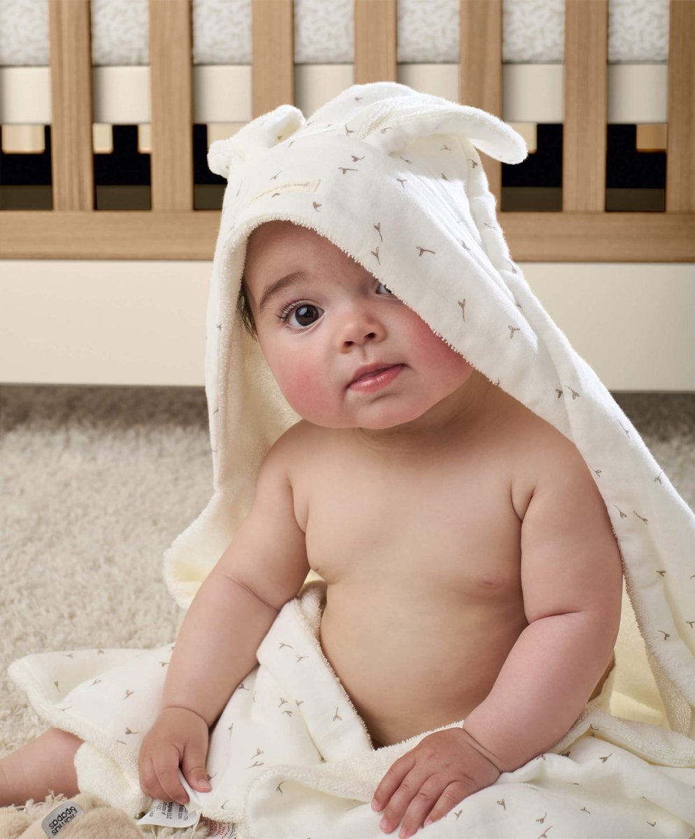 White hooded towel with small dot pattern, baby wrapped in front view