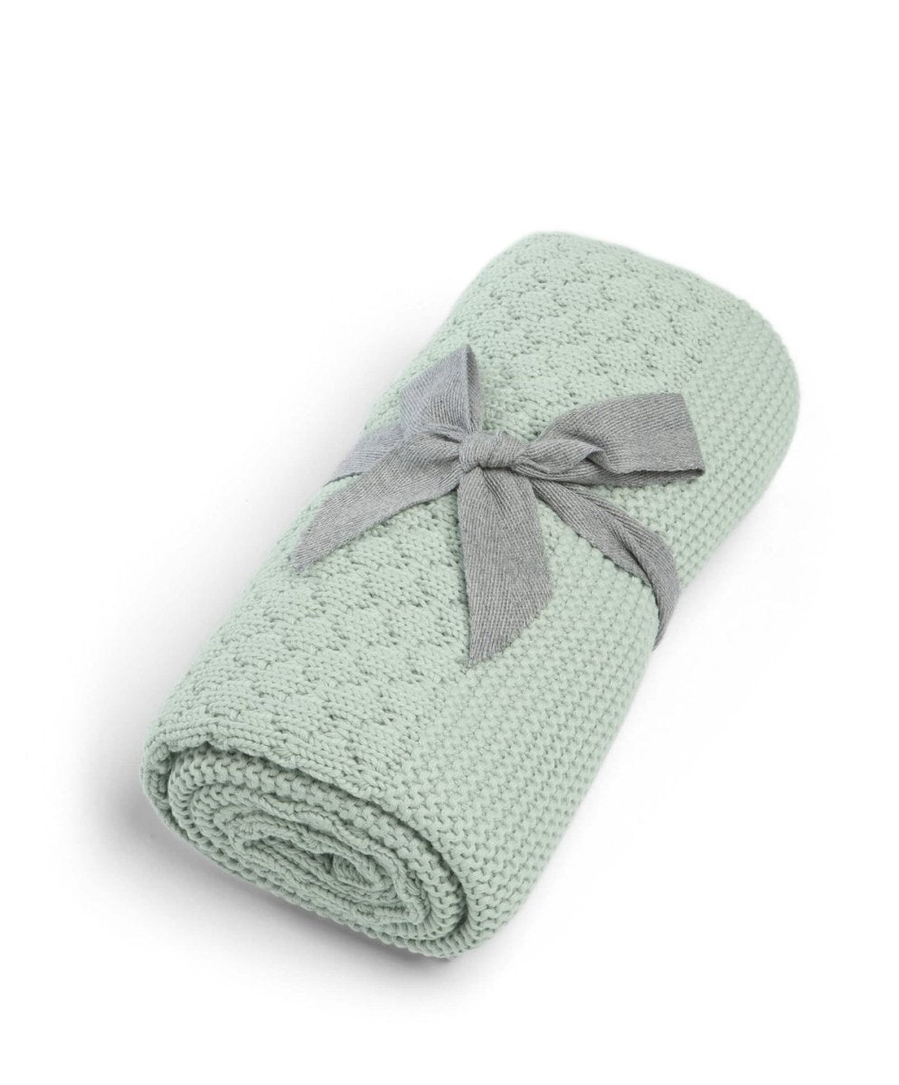 Mint green knitted blanket, rolled and tied with a gray fabric band