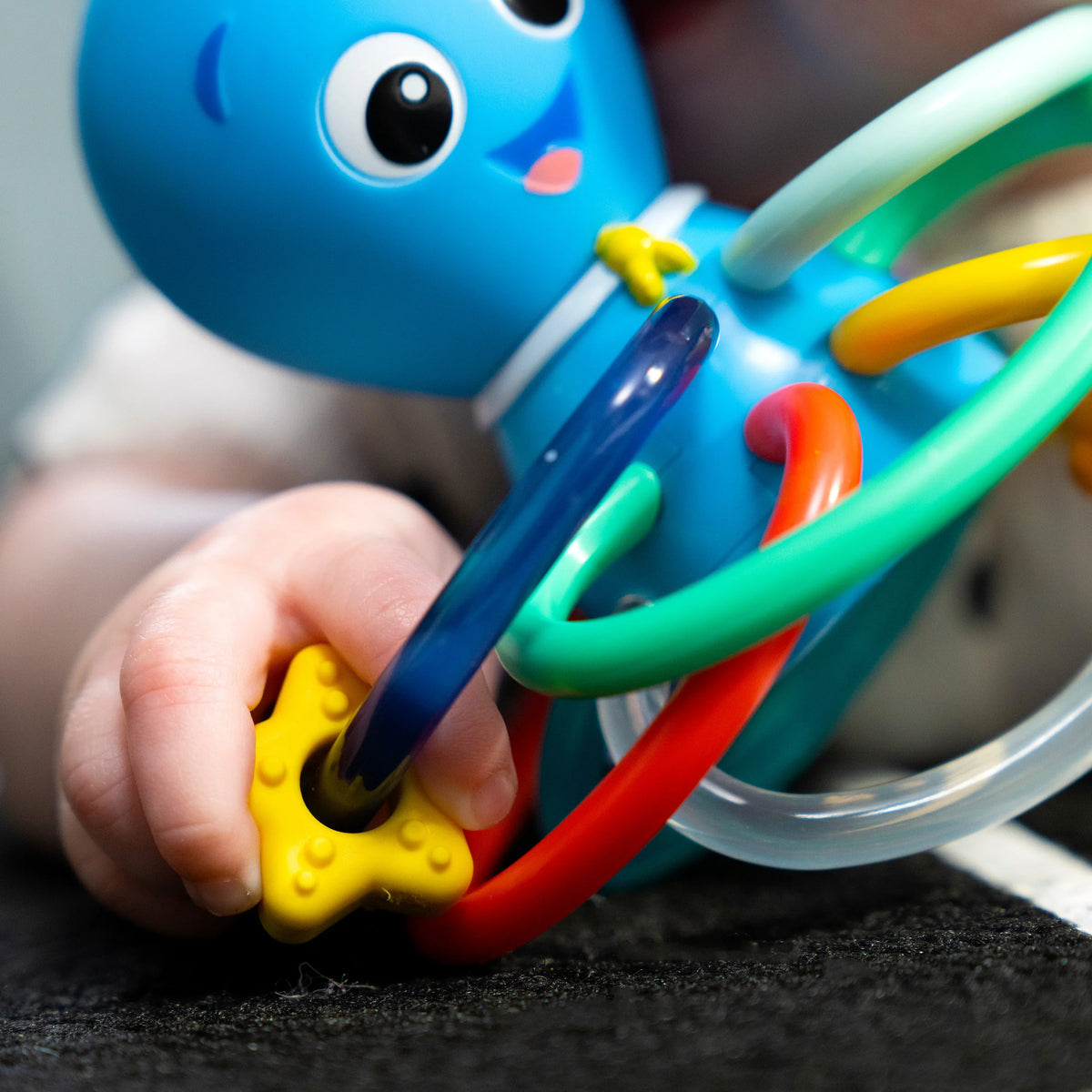 Octopus teether rattle close-up with multicolor plastic grips held in a hand