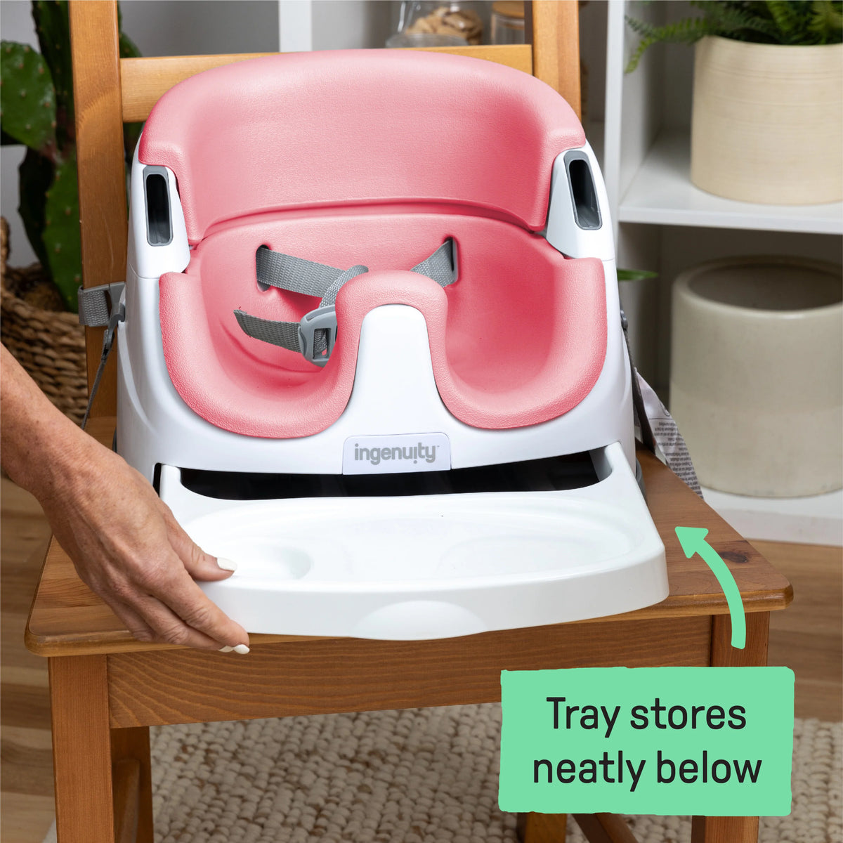 Baby booster feeding seat with pink backrest and white tray, close-up view