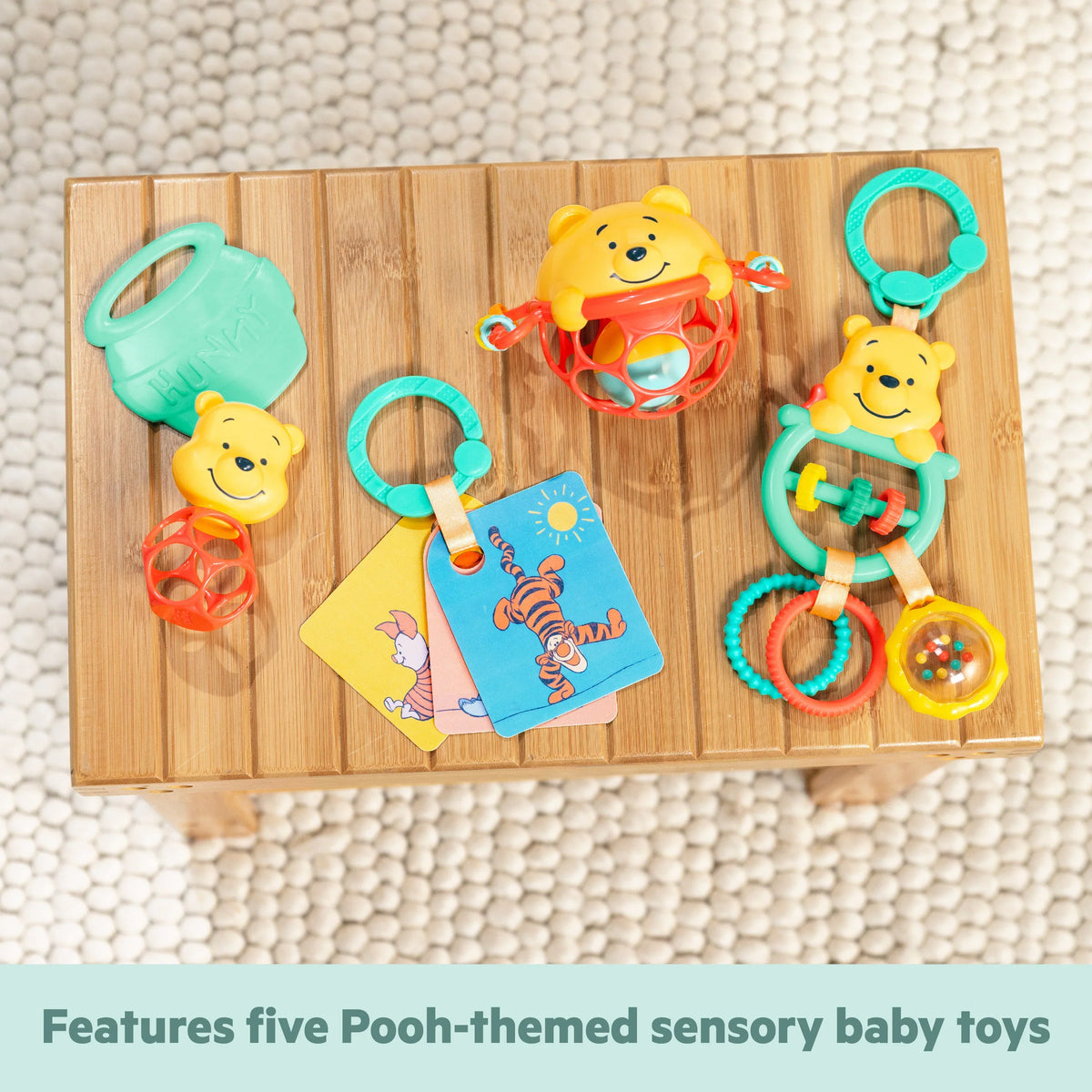 Pooh-themed sensory toy set with teether rings and activity tags on a wooden board