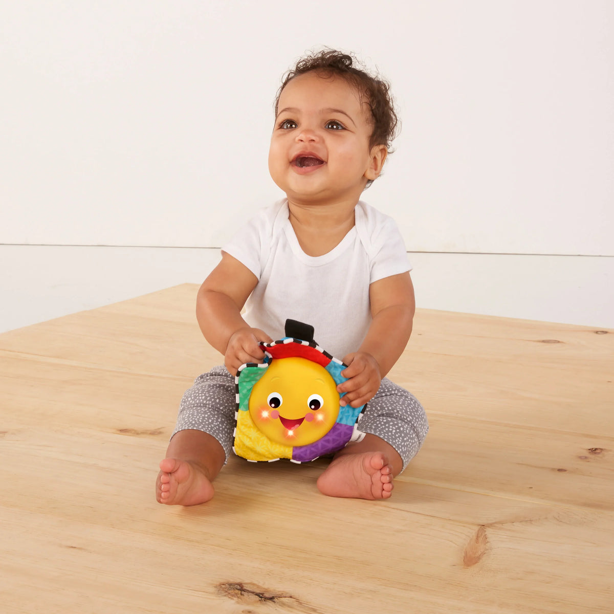 Baby holding a small plush musical take-along star toy with multicolor panels