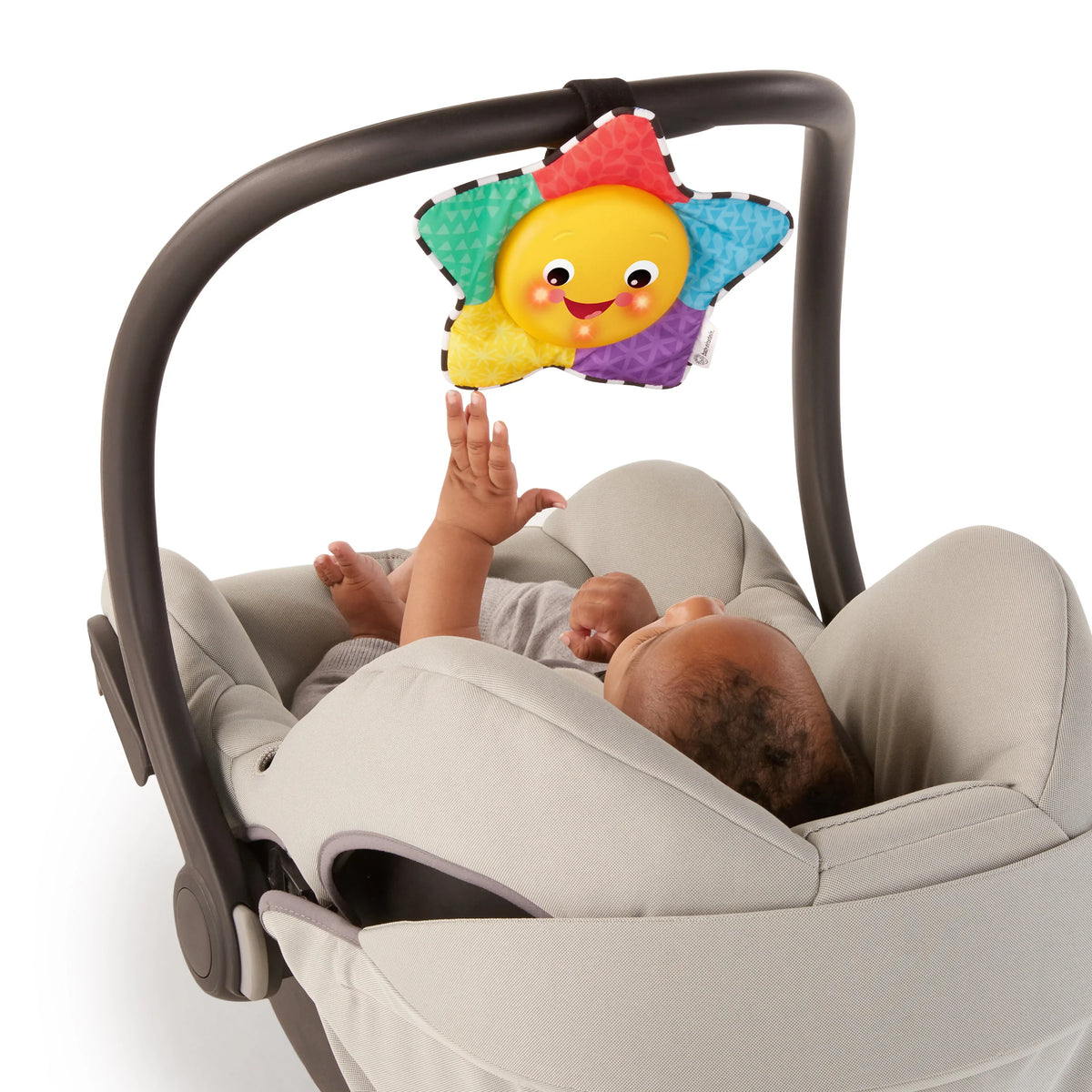 Plush star musical toy hanging from stroller bar, showing smiling yellow face