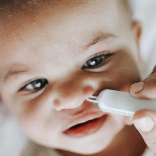 White nose care tool with teal tip held to baby’s nose