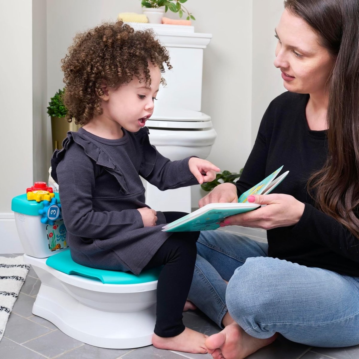 Teal potty training seat on a white base; child sits while an adult guides