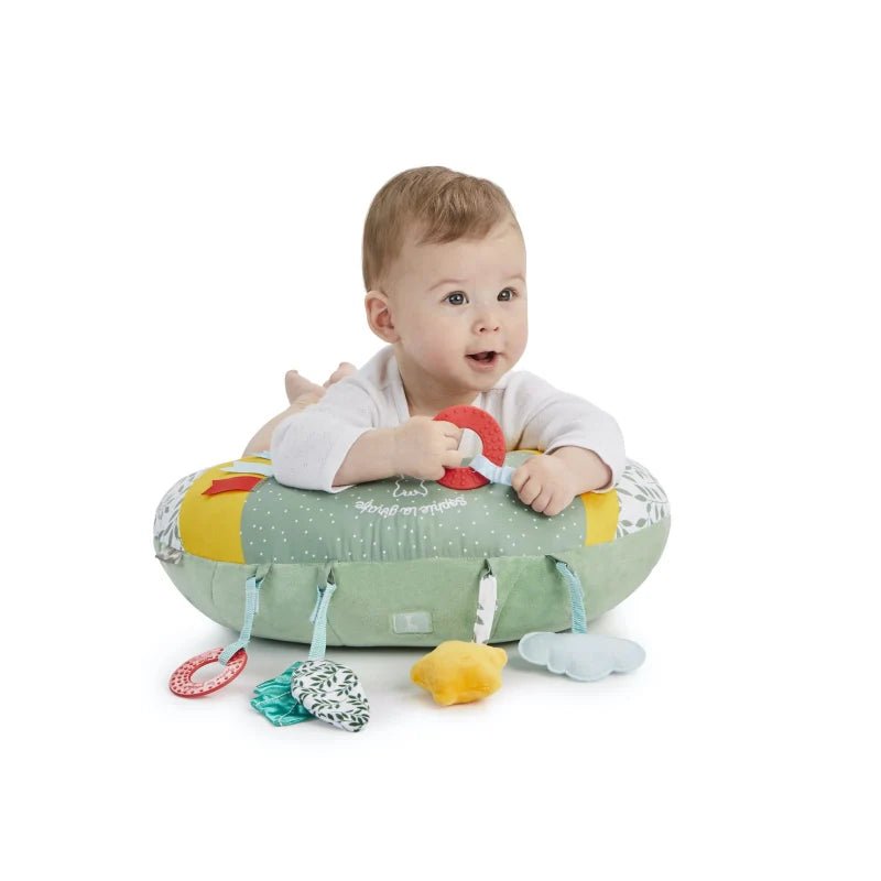 Cozy play cushion with green padded center and attached hanging toys, used by baby