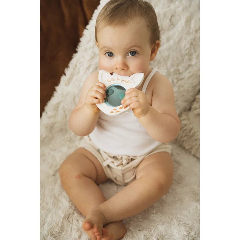 Gray giraffe magic mirror with circular reflective window, held by a baby