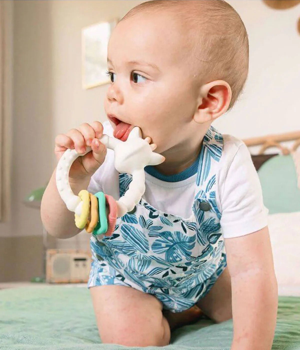 Baby holding So'Pure teething rings with green and blue textured loops