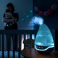 Hygro(+) baby humidifier on table with visible mist and blue LED display