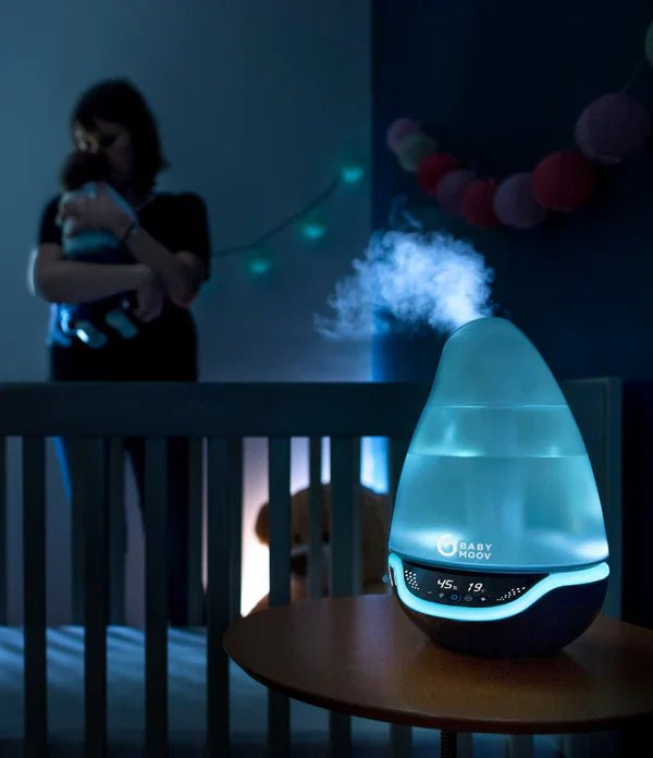 Hygro(+) baby humidifier on table with visible mist and blue LED display