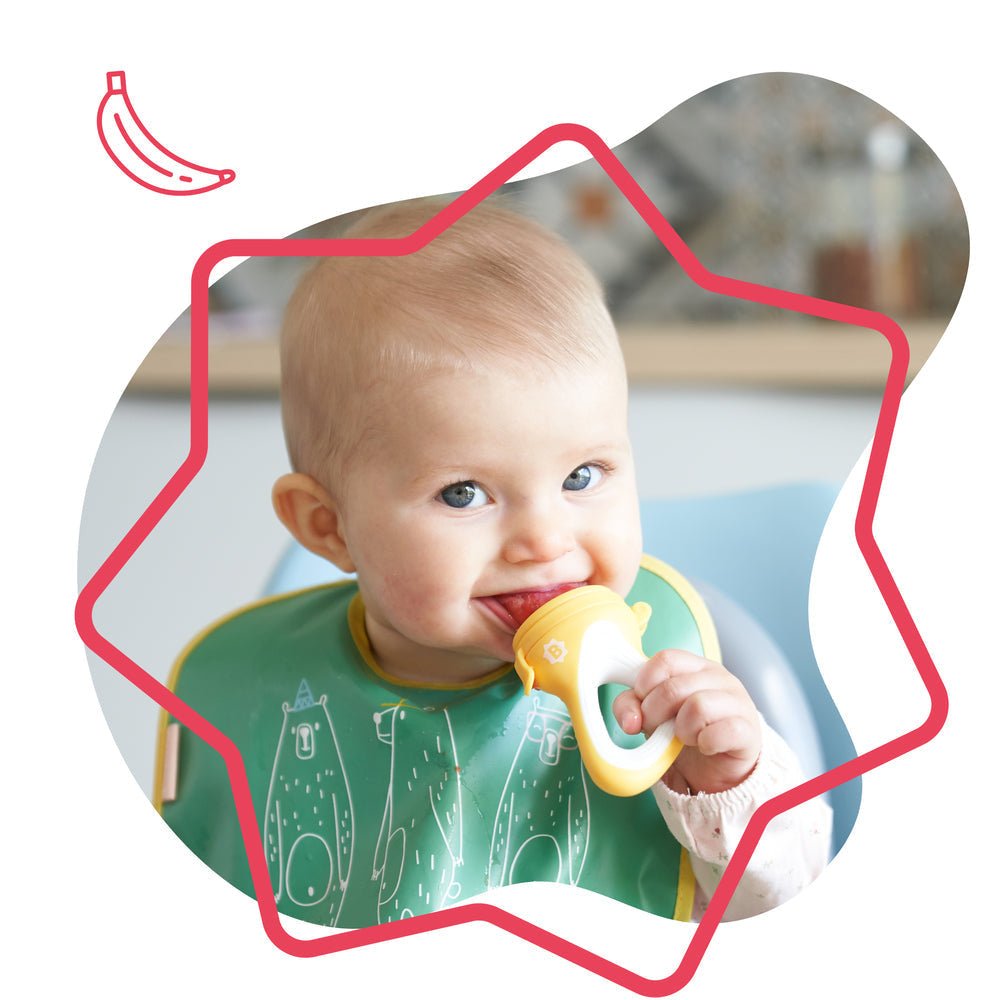 Baby holding a yellow fruit teether with white mesh cup