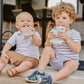 Two babies holding light-colored feeding pouches with cat faces
