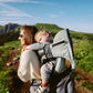 Baby hiking carrier with light-green canopy and padded shoulder straps holding child.