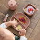 Baby weaning tray set with pink bib tray, divided plates, and spoon, on table