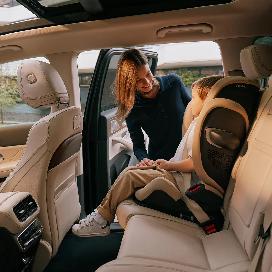 i-Size car seat with harness and padded sides, child seated beside adult
