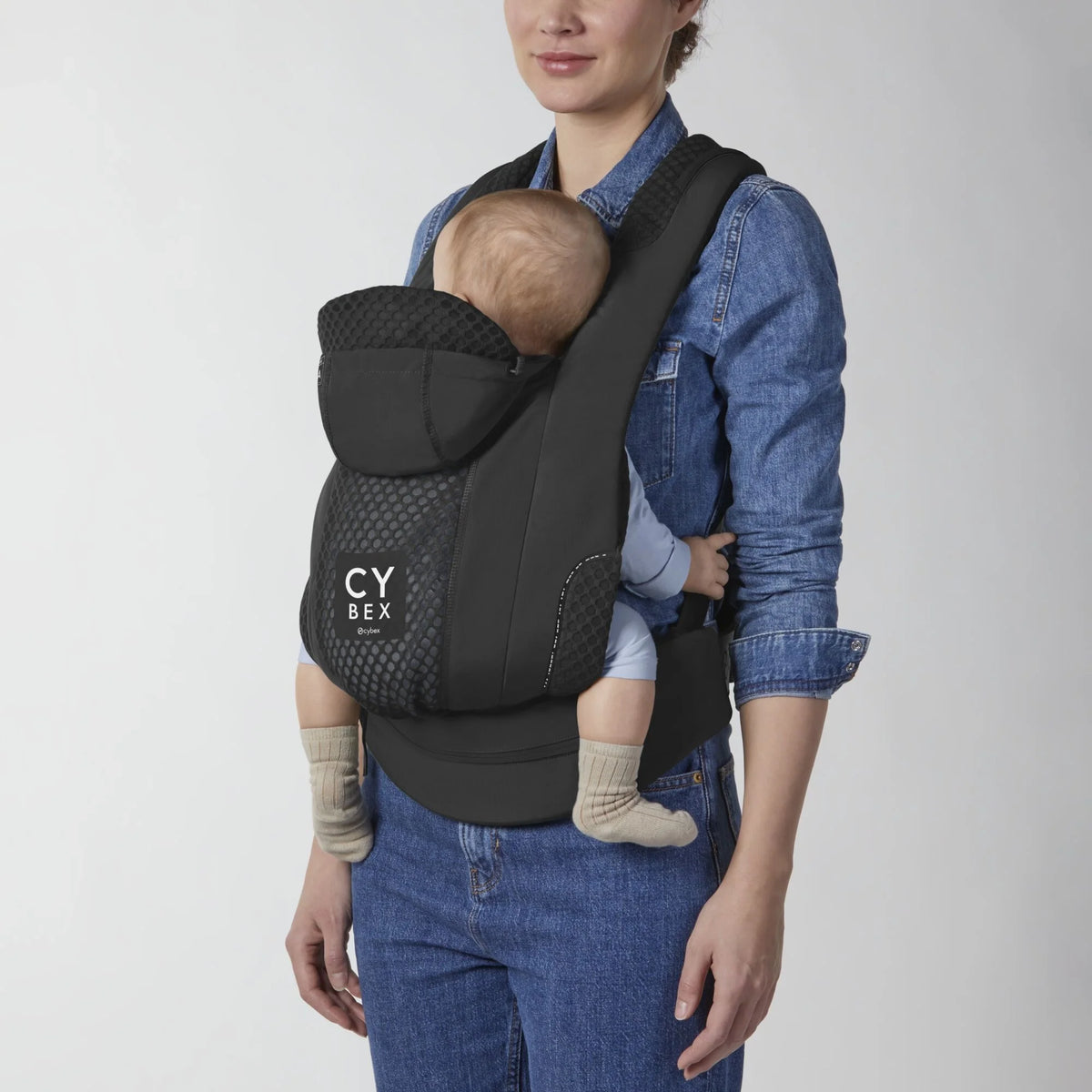 Black baby carrier with infant in seat, CYBEX logo on the front panel.