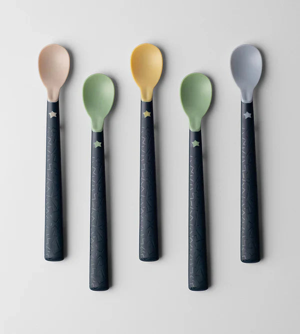 Five weaning spoons standing upright, pastel heads and dark blue textured handles with stars