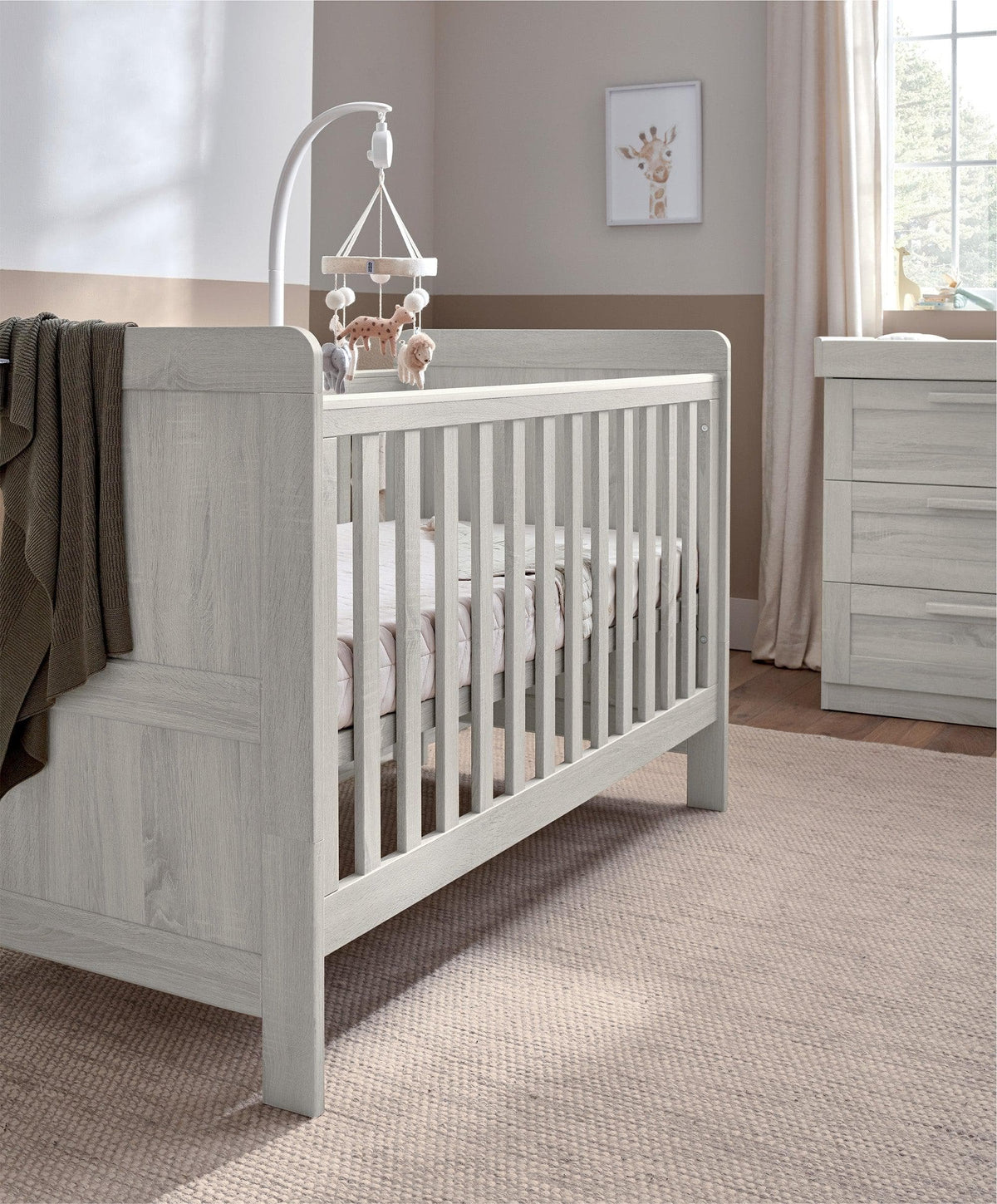 Light gray wood cotbed with vertical rails and two end panels, angled side view