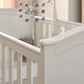 White cotbed side rail and end panel with arched headboard details.