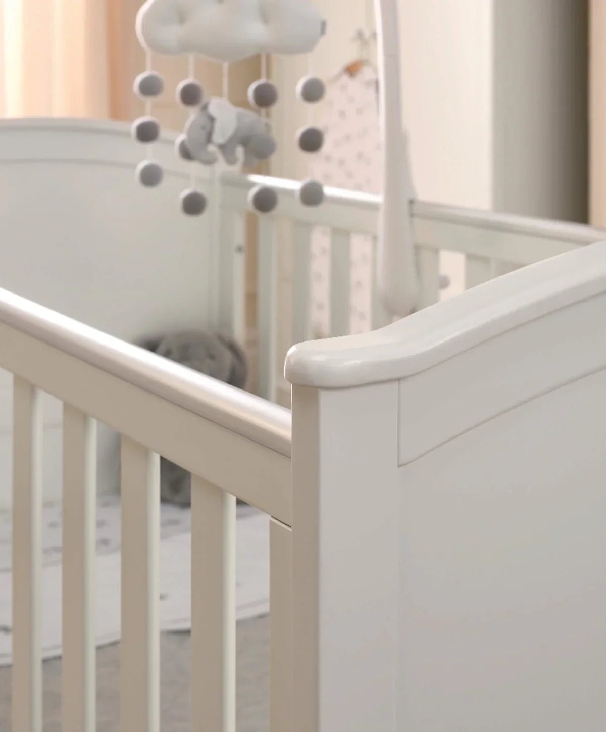White cotbed side rail and end panel with arched headboard details.