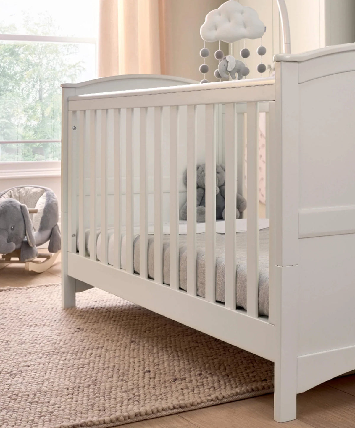 White cotbed with vertical slats and paneled side panels.
