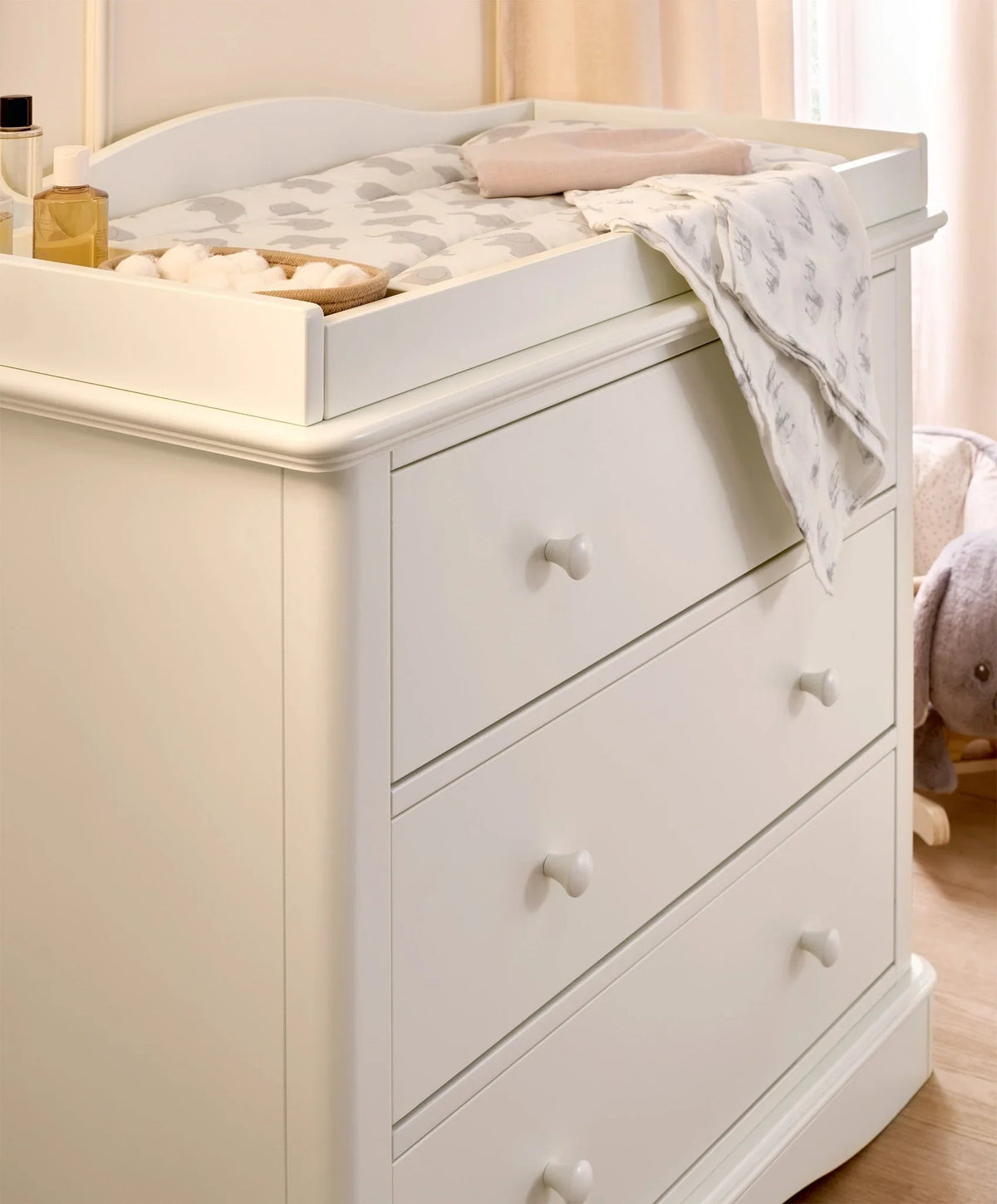 White dresser changer close-up with three drawers, knob pulls, and raised top